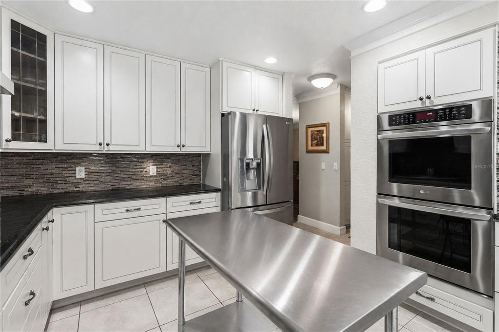 A kitchen features white cabinets, dark countertops, stainless steel appliances, and a metal island — 5333 GREENSIDE COURT, ORLANDO, FL