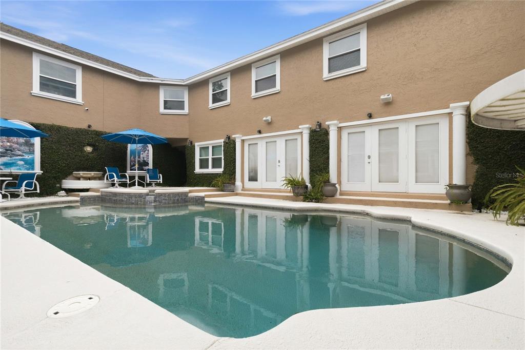 A swimming pool sits in front of a two-story house with tan stucco walls — 5333 GREENSIDE COURT, ORLANDO, FL