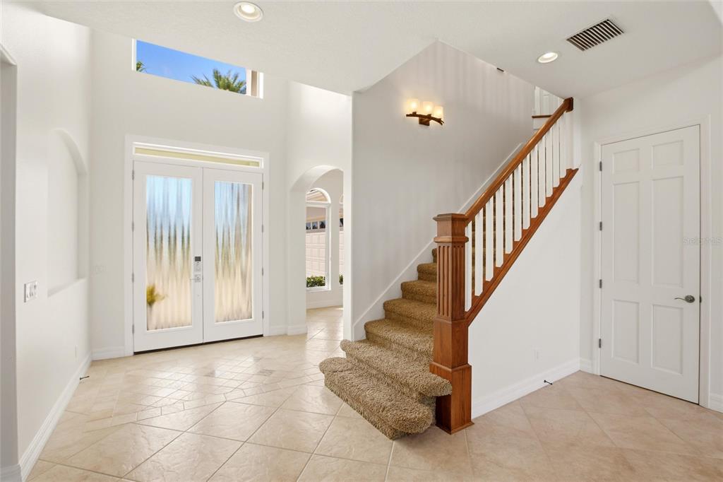 An entryway features a tiled floor, a carpeted staircase with a wooden railing, and double doors — 8417 LONE EAGLE WAY, SARASOTA, FL