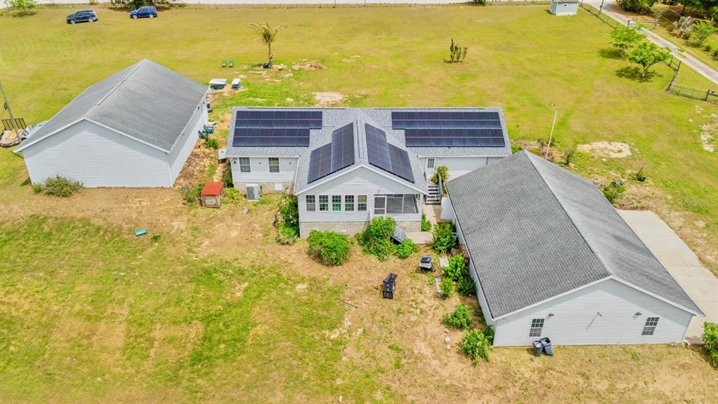 An aerial view of a house with solar panels on the roof and a detached garage — 37520 PHELPS ROAD, ZEPHYRHILLS, FL