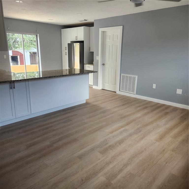 A kitchen with a granite-topped island and light wood-look flooring opens into a dining area — 12230 SKYLER LANE, SPRING HILL, FL