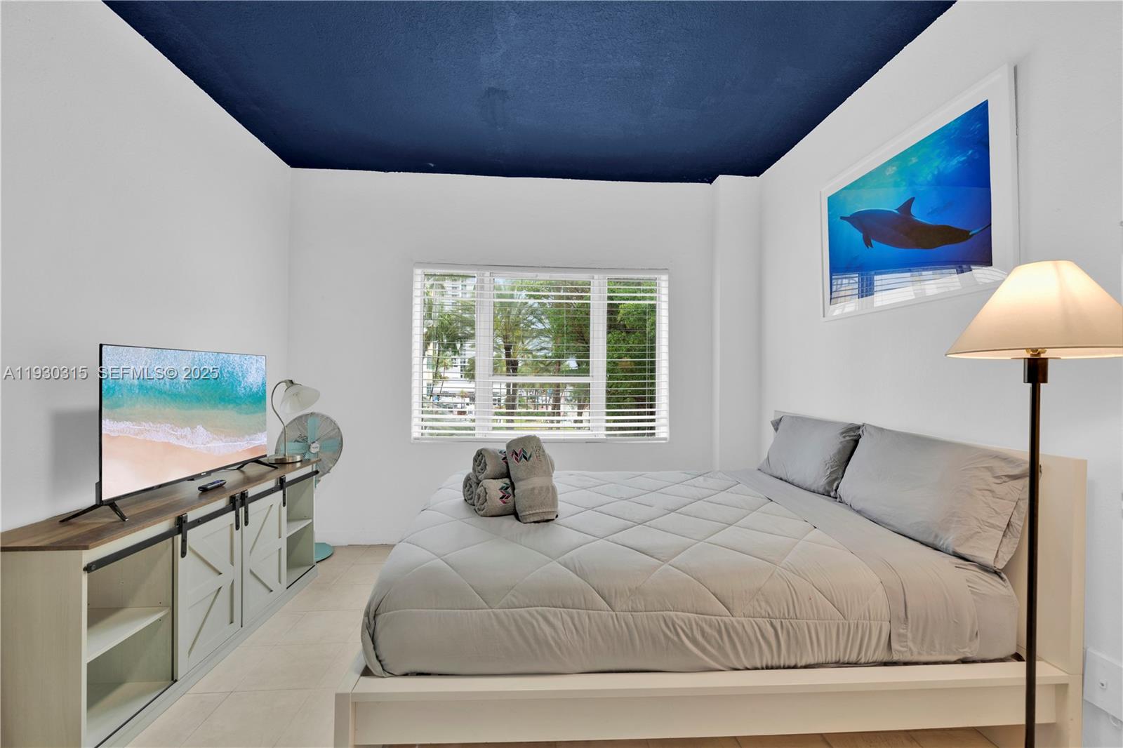 A bedroom features a bed with grey bedding, a television on a console, and a blue ceiling — 255 W 24th St # 302, Miami Beach FL 33140, MIAMI BEACH, FL