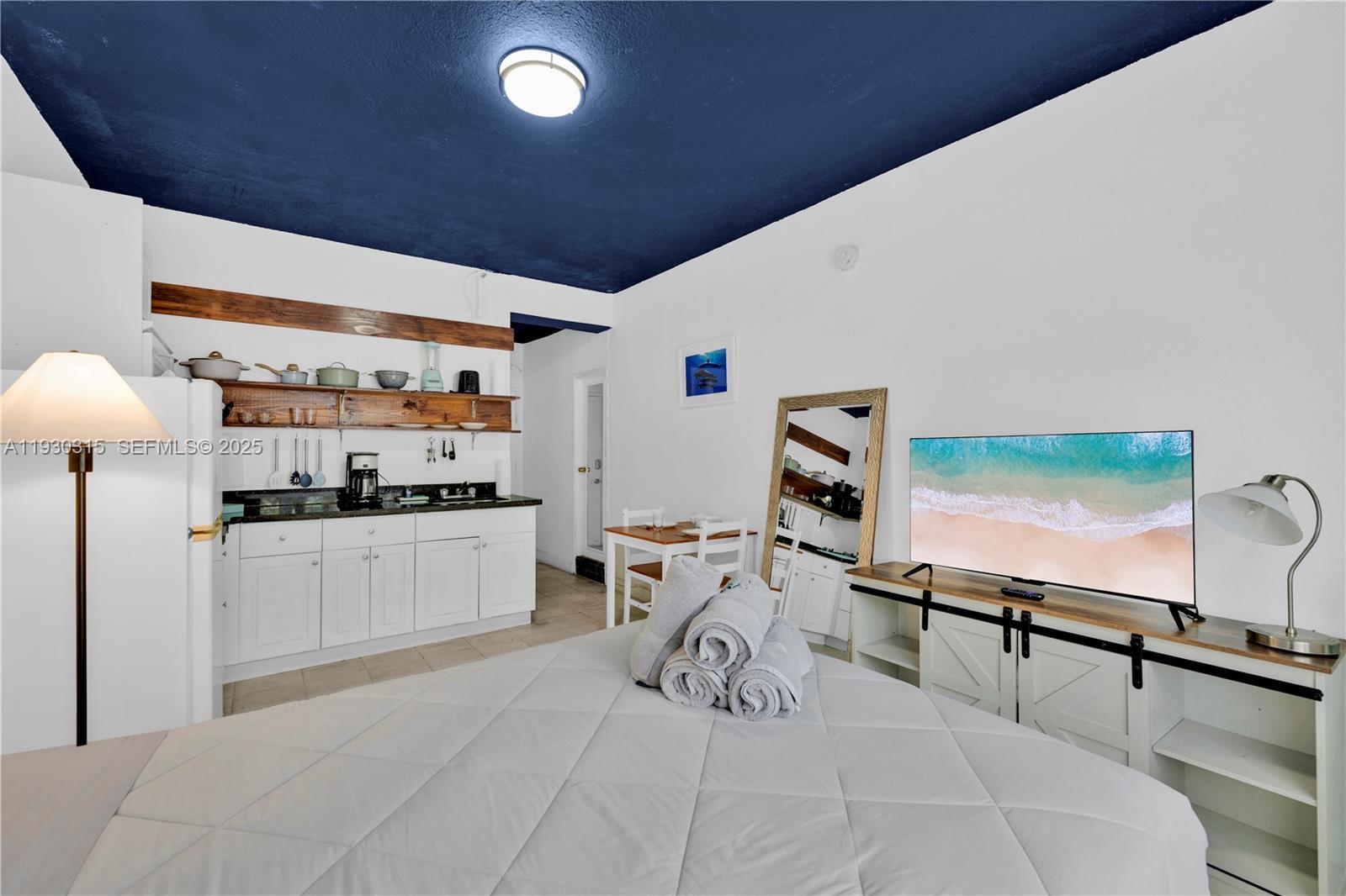 A studio apartment features a kitchenette, a bed with towels, and a dark blue ceiling — 255 W 24th St # 302, Miami Beach FL 33140, MIAMI BEACH, FL