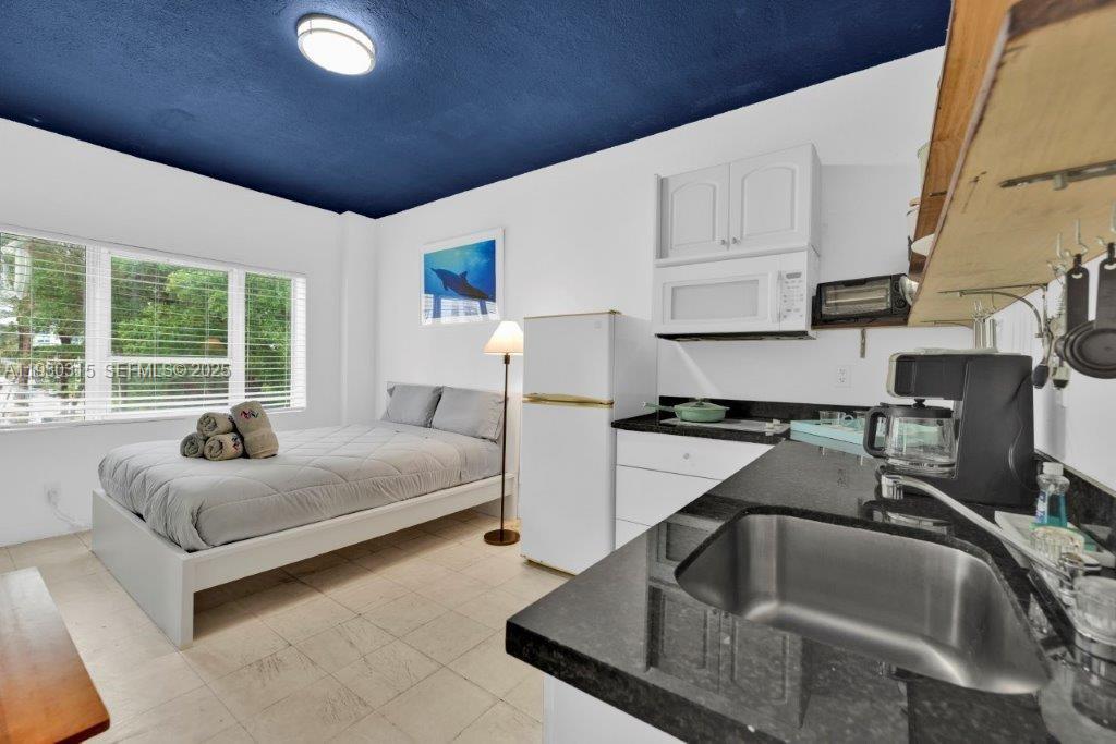 A studio apartment features a kitchenette with black countertops, a bed, and a blue ceiling — 255 W 24th St # 302, Miami Beach FL 33140, MIAMI BEACH, FL