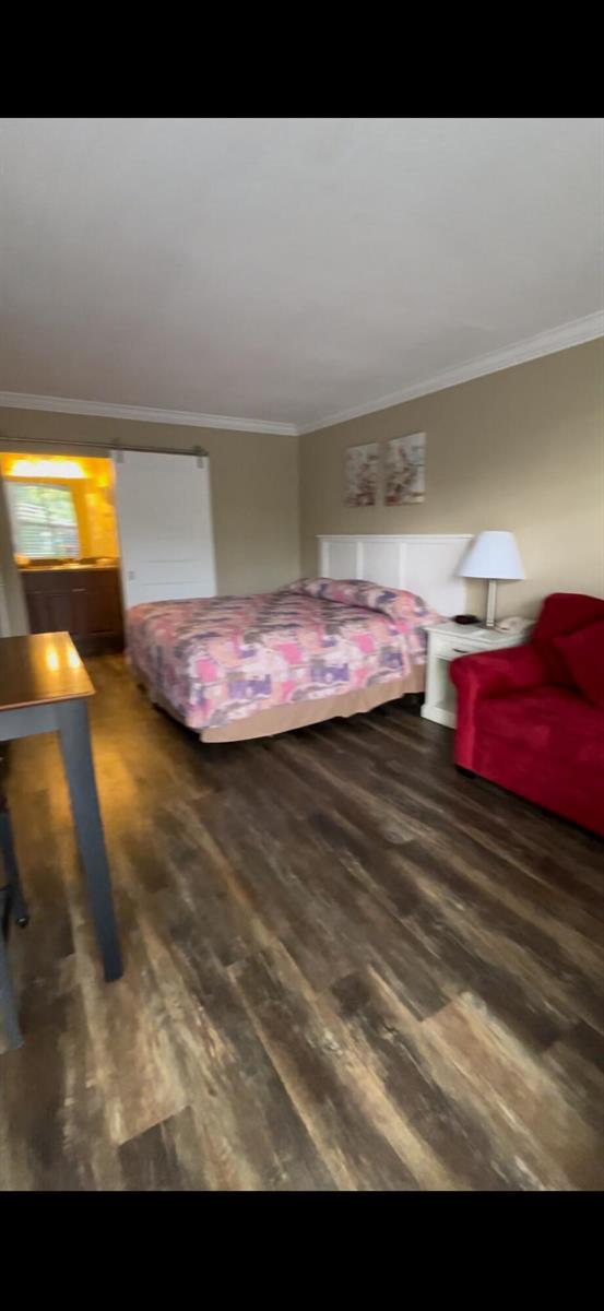 A bedroom features wood-look flooring, a bed with a patterned quilt, and a red sofa — 2555 9th Street N # 152, Naples FL 34103, NAPLES, FL