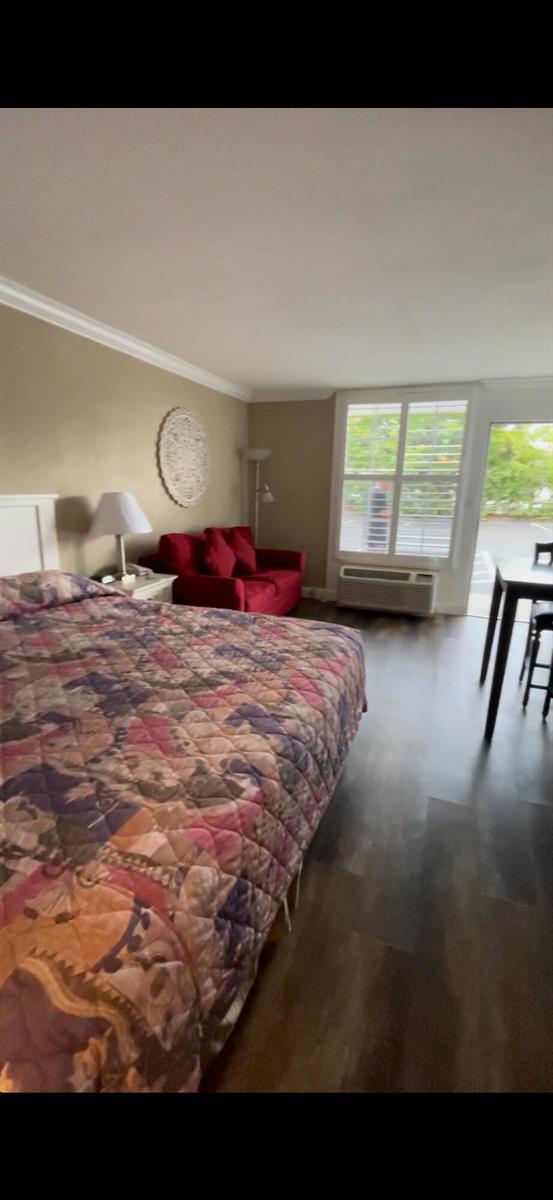 A bedroom with a patterned quilt on the bed, a red sofa, and wood flooring — 2555 9th Street N # 152, Naples FL 34103, NAPLES, FL
