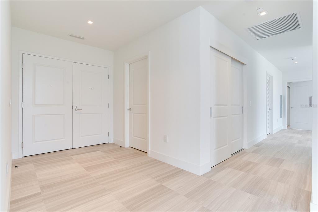 A bright hallway features white walls, light wood-look tile flooring, and several white interior doors — 3015 S YSABELLA AVENUE UNIT 2401, TAMPA, FL