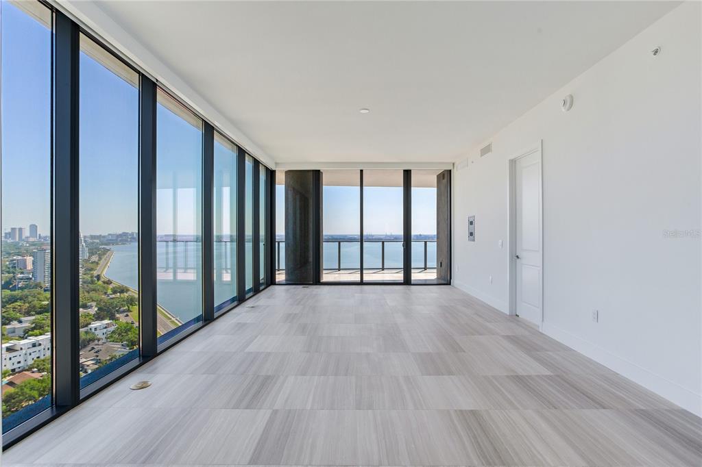 An empty room features floor-to-ceiling windows, light-colored tile flooring, and a view of water — 3015 S YSABELLA AVENUE UNIT 2401, TAMPA, FL