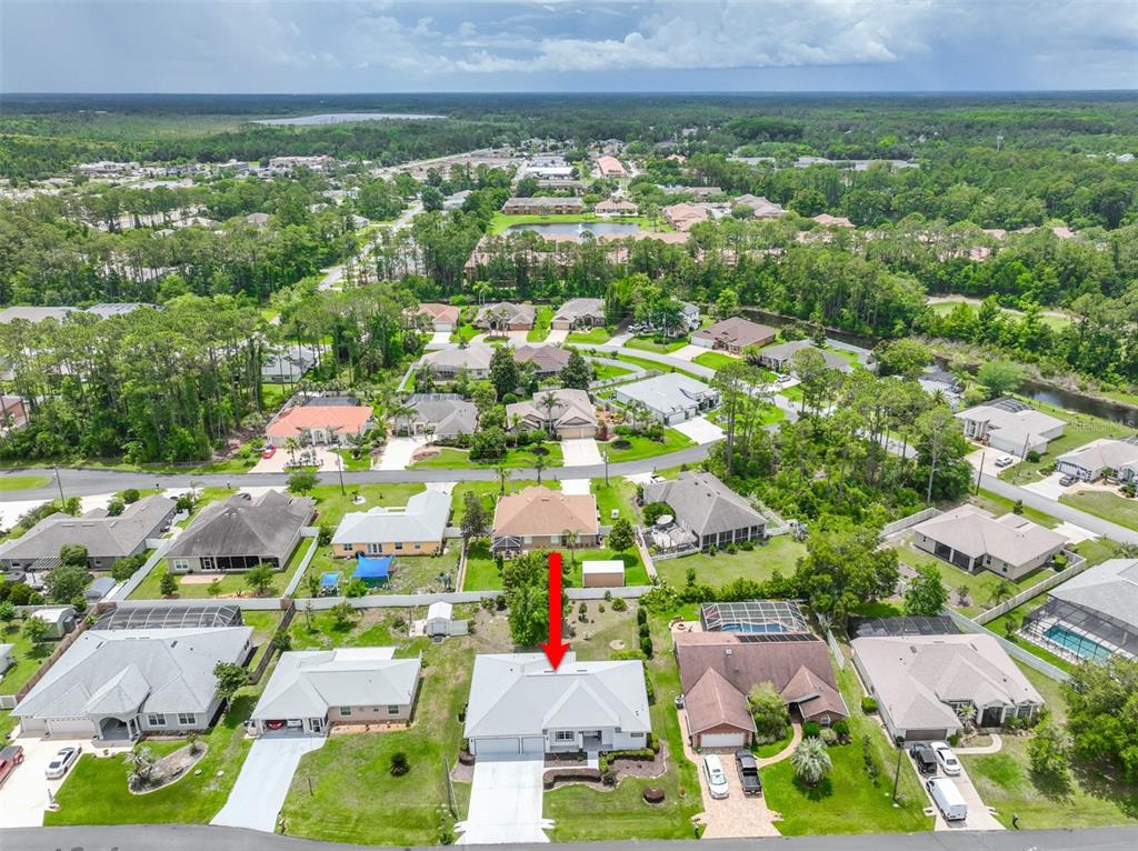 An aerial view shows a suburban neighborhood with a red arrow pointing to a house — 8 EASTGATE LANE, PALM COAST, FL