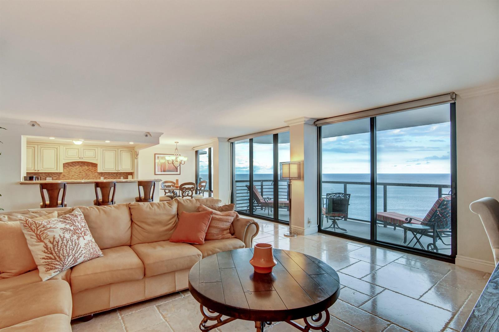 A living room with a beige sectional, round wooden coffee table, and oceanfront balcony access — 250 S Ocean Boulevard # c, Boca Raton FL 33432, BOCA RATON, FL