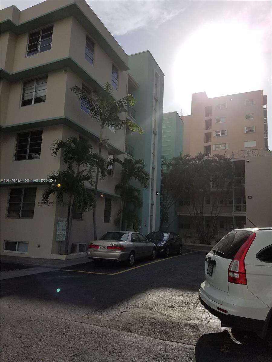 An exterior view of a multi-story apartment building with a parking lot in front — 1751 Washington Ave # 1H, Miami Beach FL 33139, MIAMI BEACH, FL