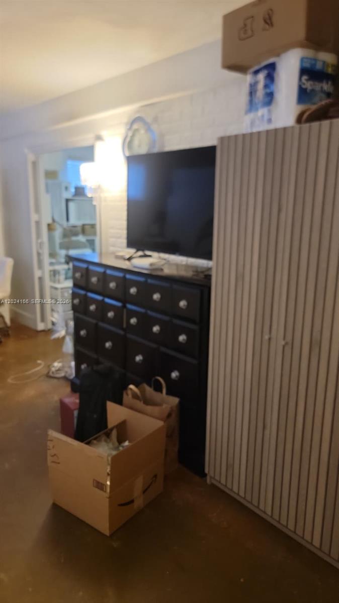 A room features a dark dresser topped with a television, a tall cabinet, and cardboard boxes — 1751 Washington Ave # 1H, Miami Beach FL 33139, MIAMI BEACH, FL