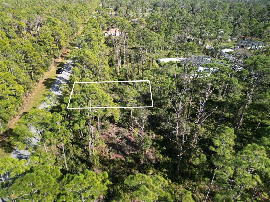 An aerial view shows a rectangular plot of land outlined in white amidst dense woods — 0 KAMSLER AVENUE, NORTH PORT, FL