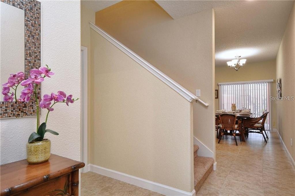 A foyer with a staircase, a potted orchid, and a view into a dining area — 2973 BANANA PALM DRIVE, KISSIMMEE, FL