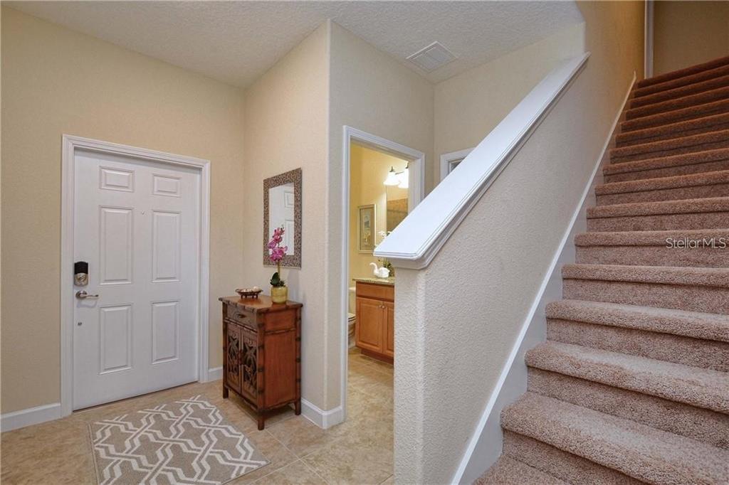 An entryway features a white front door, a small wooden cabinet, and carpeted stairs — 2973 BANANA PALM DRIVE, KISSIMMEE, FL