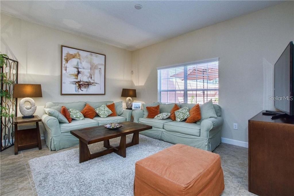 A living room features two light green sofas, a wooden coffee table, and an ottoman — 2973 BANANA PALM DRIVE, KISSIMMEE, FL