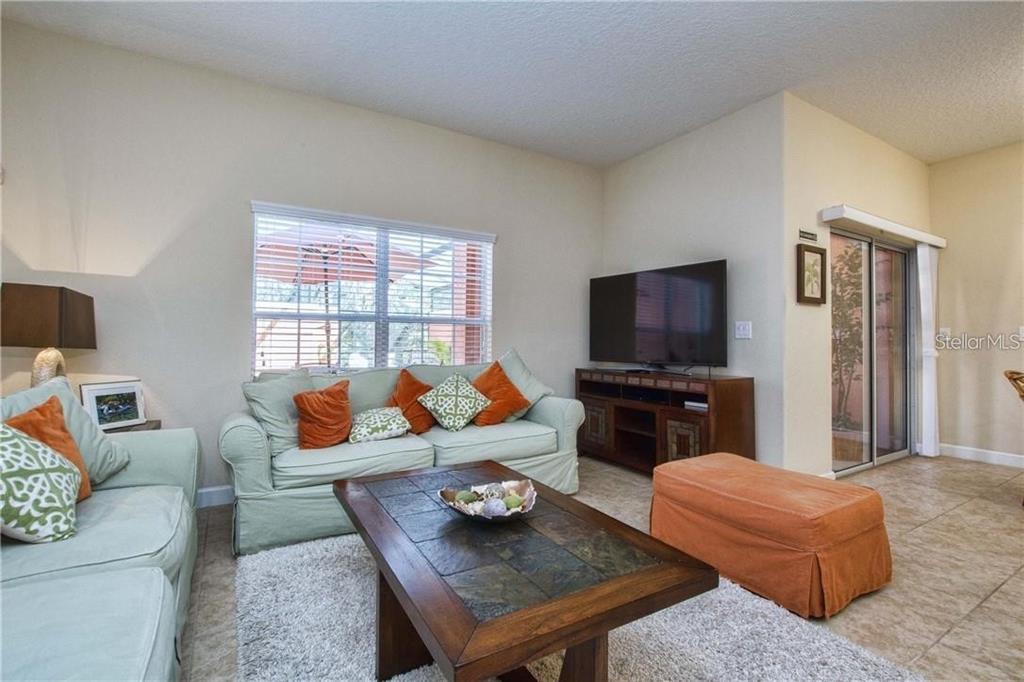 A living room features a light green sofa, a tile-topped coffee table, and a television — 2973 BANANA PALM DRIVE, KISSIMMEE, FL