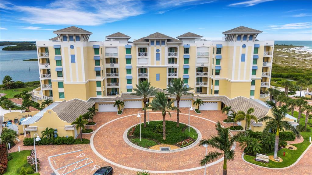 An aerial view of a multi-story yellow apartment building with a circular brick driveway — 795 COLLANY ROAD UNIT 304, ST PETERSBURG, FL