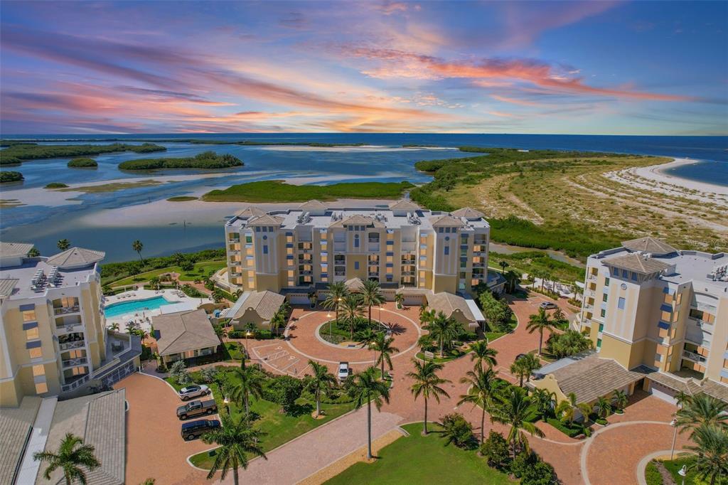 An aerial view of a multi-story apartment complex with a pool and coastal landscape — 795 COLLANY ROAD UNIT 304, ST PETERSBURG, FL