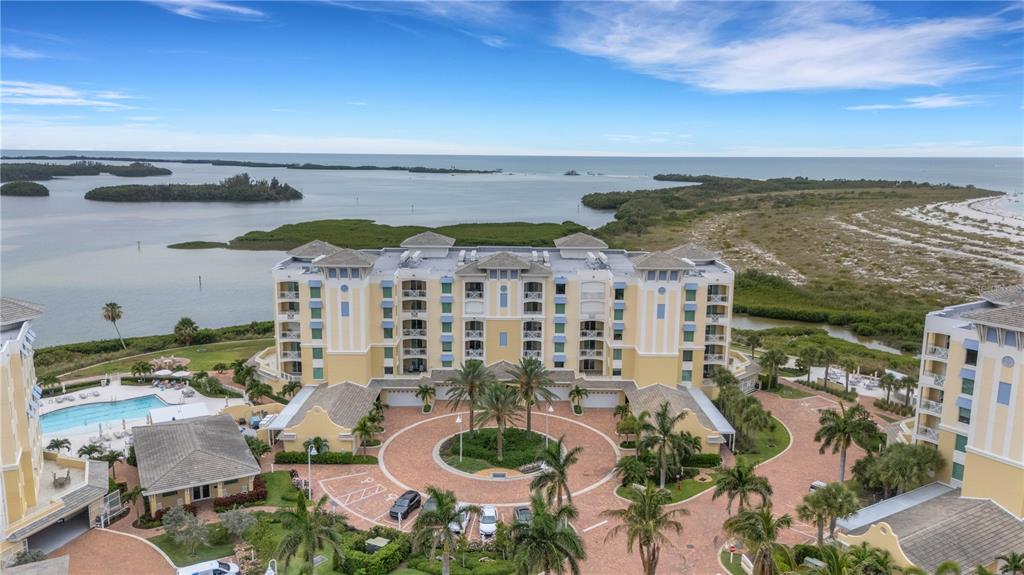 An aerial view shows a multi-story yellow resort building with a circular brick courtyard — 795 COLLANY ROAD UNIT 304, ST PETERSBURG, FL