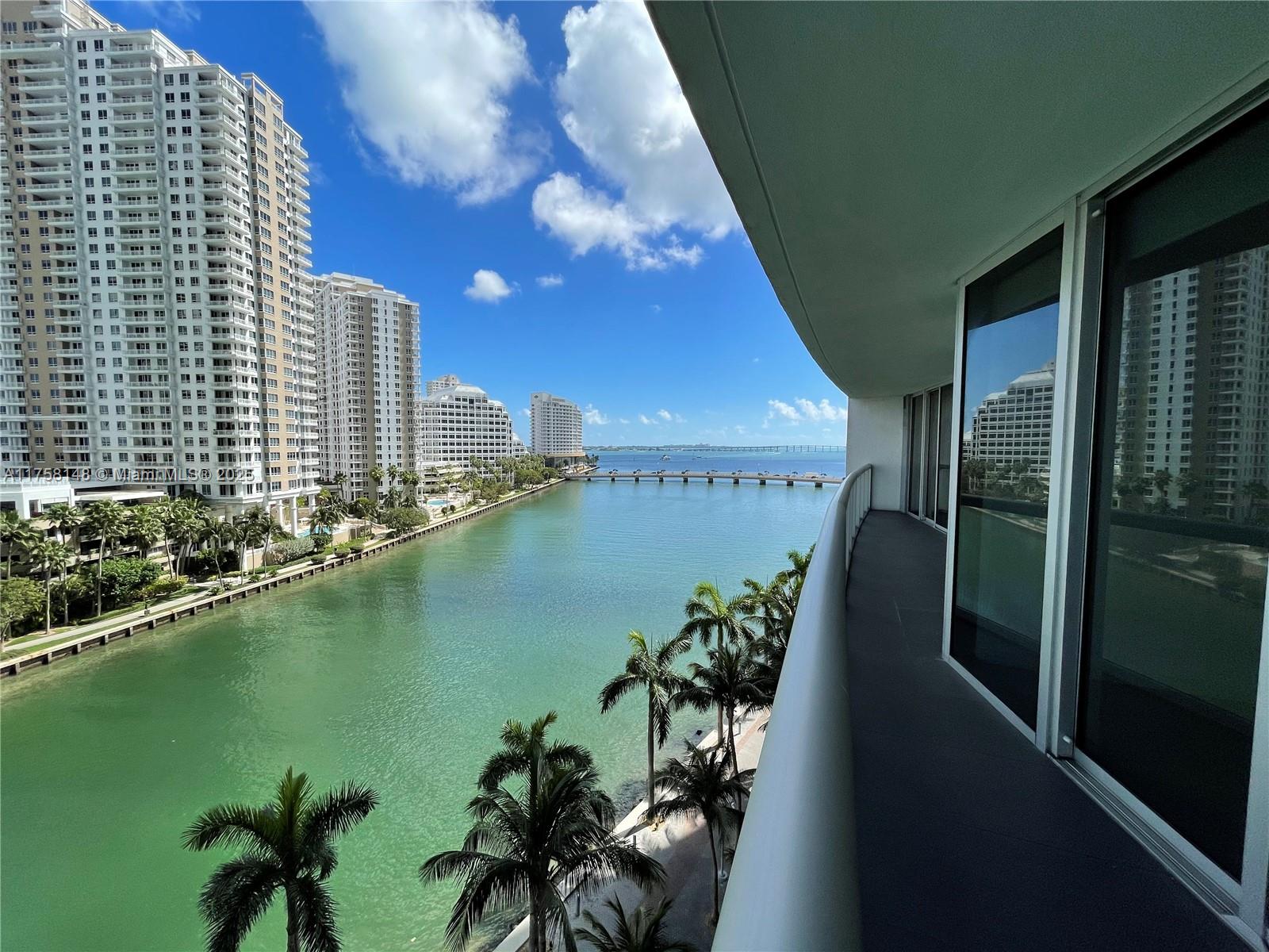 A balcony overlooks a canal, palm trees, high-rise buildings, and a distant bridge — 465 Brickell Ave # 819, Miami FL 33131, MIAMI, FL