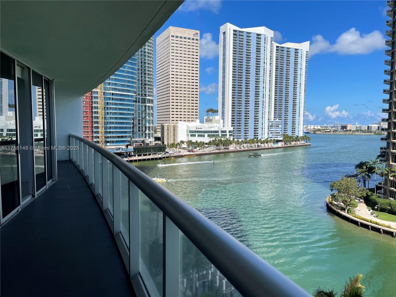 A balcony with a glass railing overlooks a river and city skyline — 465 Brickell Ave # 819, Miami FL 33131, MIAMI, FL