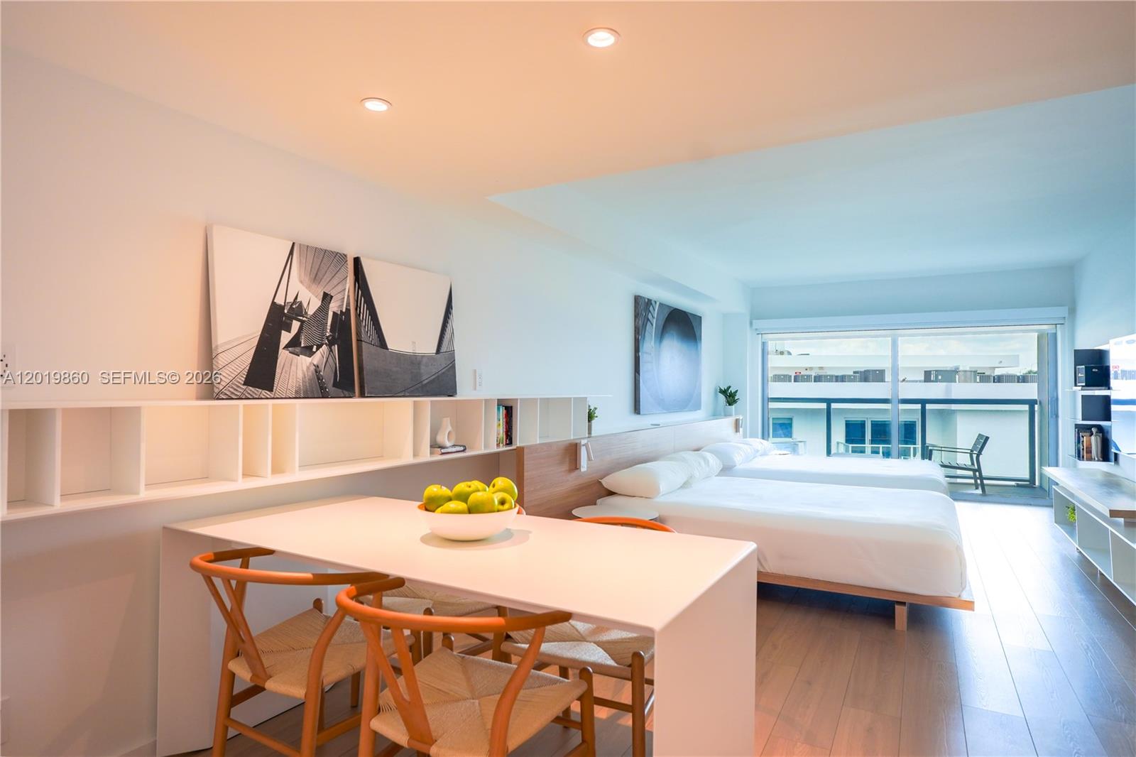 A modern bedroom features a dining table, two beds, and a balcony with outdoor seating — 10250 Collins Avenue # 407, Bal Harbour FL 33154, BAL HARBOUR, FL