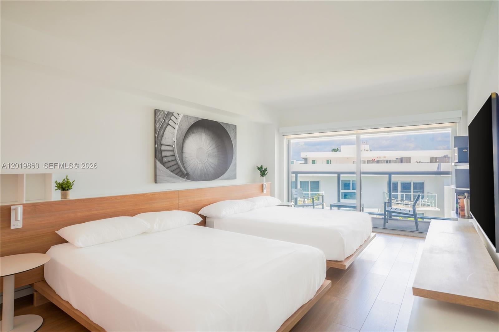 A bedroom features two beds, a wooden headboard, and a balcony with outdoor seating — 10250 Collins Avenue # 407, Bal Harbour FL 33154, BAL HARBOUR, FL
