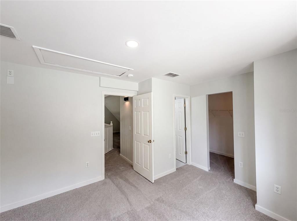 A carpeted bedroom features a closet, two doorways, and an attic access panel on the ceiling — 9701 BLACK BEAR COURT, NEW PORT RICHEY, FL