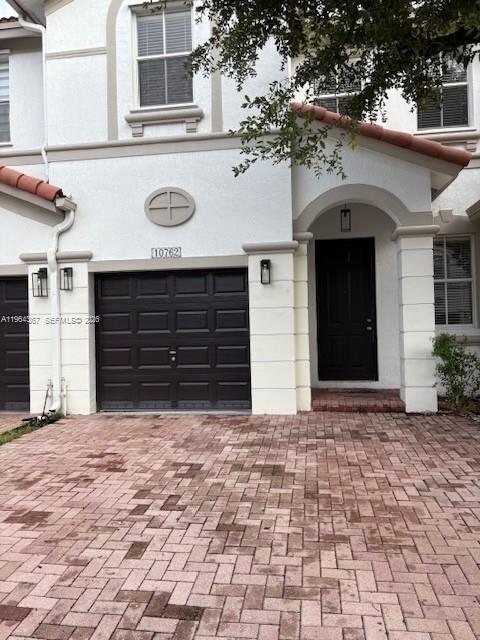 The exterior of a two-story townhouse features a dark garage door and a front entrance — 10762 NW 80th Ln, Doral FL 33178, DORAL, FL