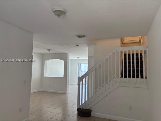 An interior view shows a tiled living area with a staircase and an arched cutout — 10762 NW 80th Ln, Doral FL 33178, DORAL, FL