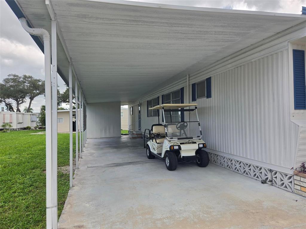 A white golf cart is parked under a covered carport attached to a mobile home — 3415 SPANISH OAK TERRACE, SARASOTA, FL
