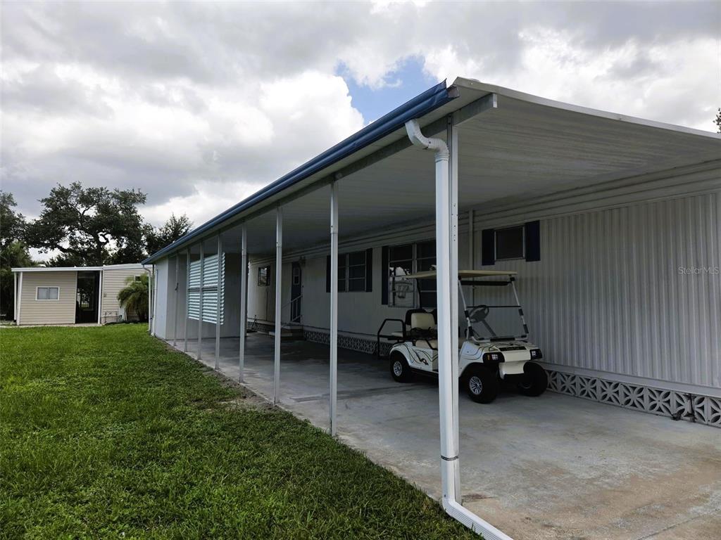 A mobile home with a long carport and a golf cart parked on the concrete driveway — 3415 SPANISH OAK TERRACE, SARASOTA, FL