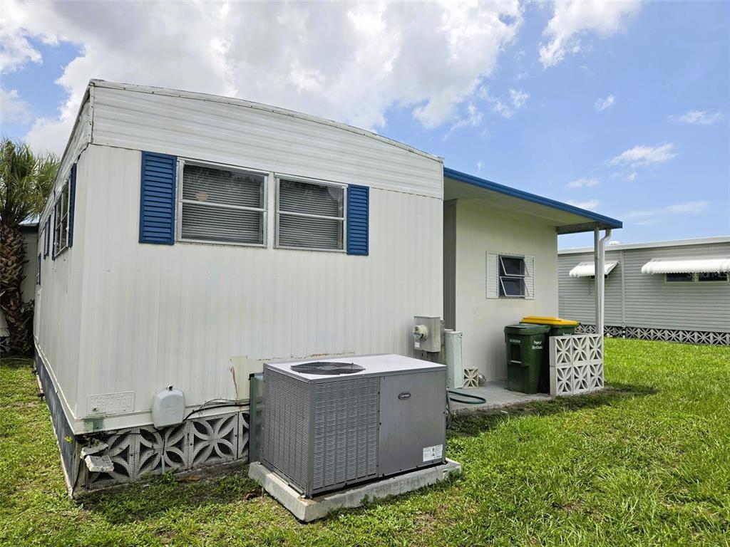 The exterior of a mobile home features white siding, blue shutters, and an air conditioning unit — 3415 SPANISH OAK TERRACE, SARASOTA, FL