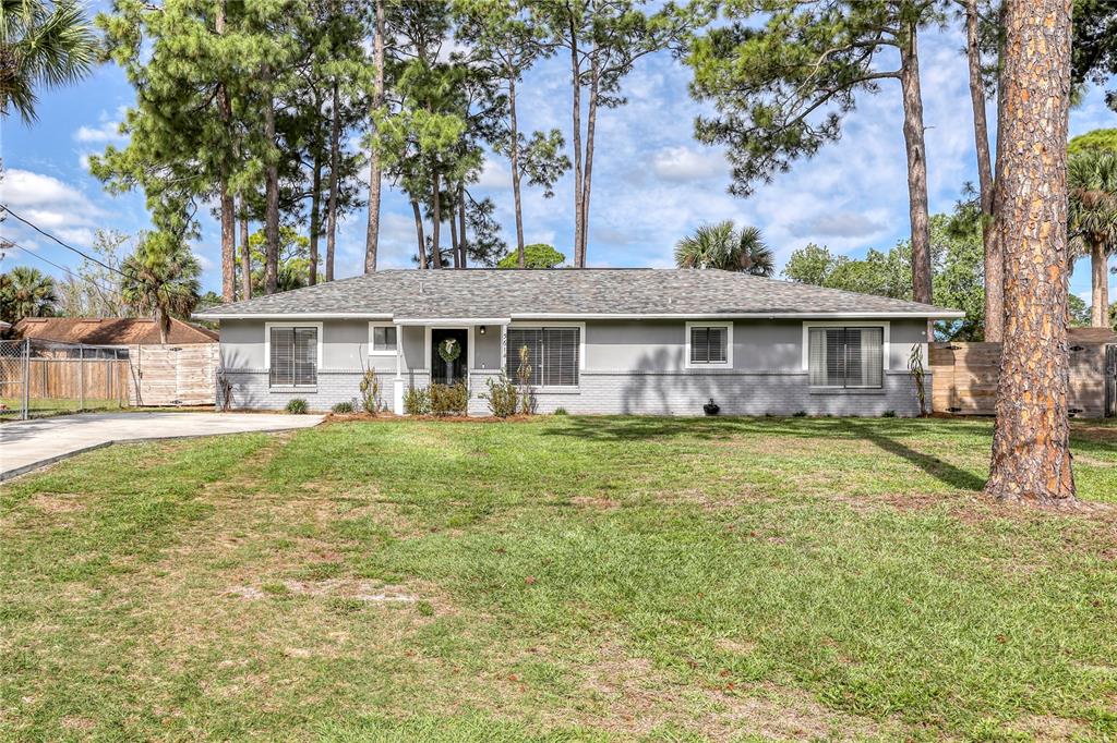 A single-story gray house with a brick base and a shingled roof sits on grass — 5614 JAMAICA ROAD, COCOA, FL