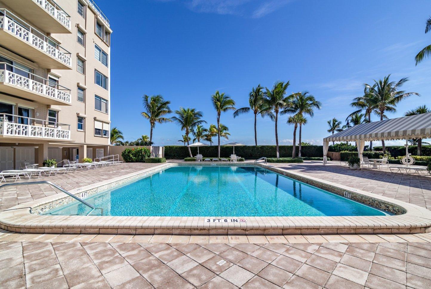 A rectangular swimming pool sits on a paved patio beside a multi-story residential building — 170 N Ocean Boulevard Boulevard # 411, Palm Beach FL 33480, PALM BEACH, FL