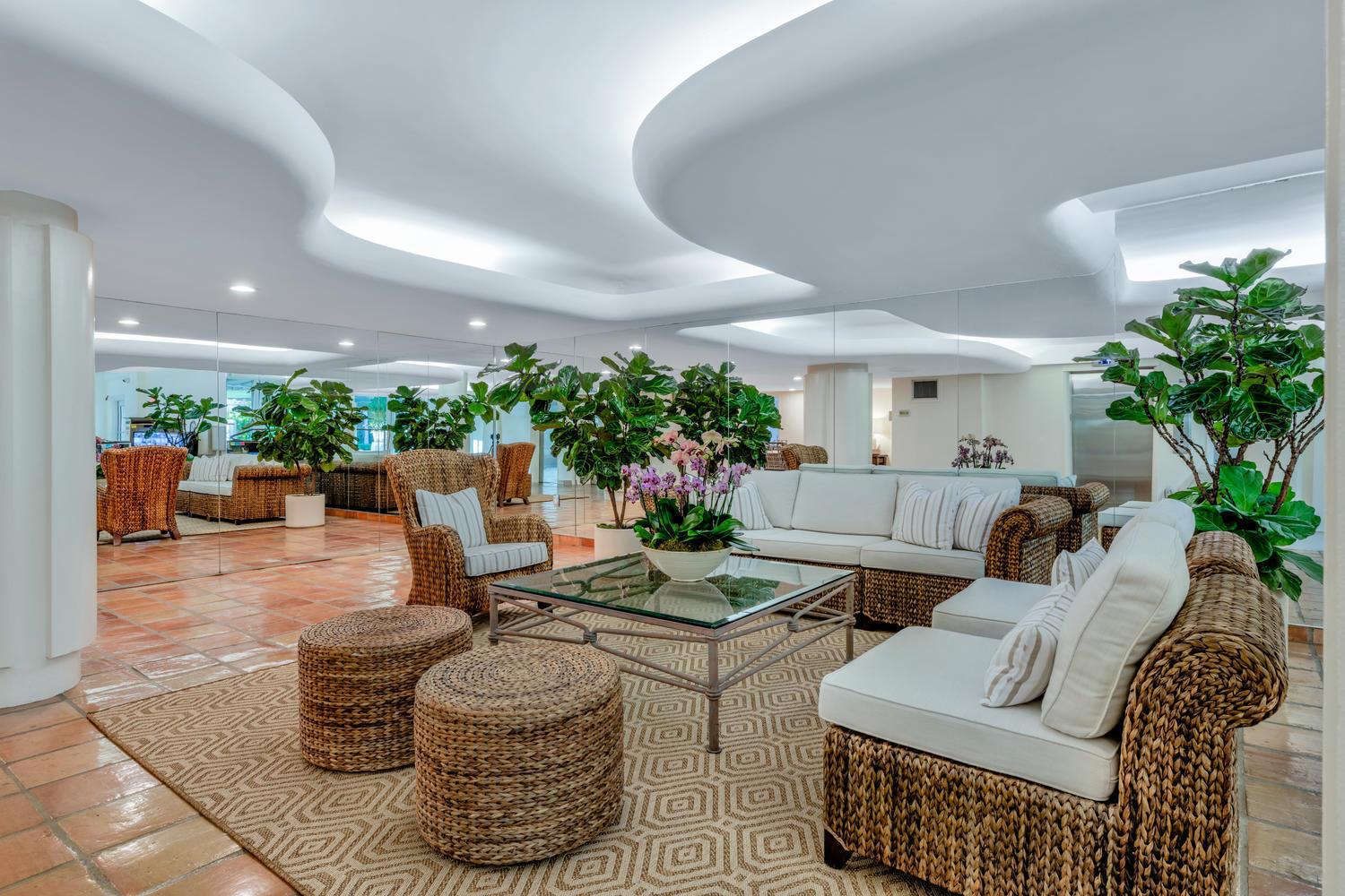 A lobby area features wicker furniture, a glass coffee table, and a wavy ceiling design — 170 N Ocean Boulevard Boulevard # 411, Palm Beach FL 33480, PALM BEACH, FL