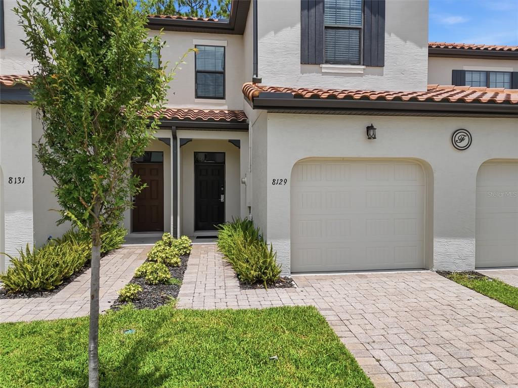 A two-story townhouse exterior features a paved driveway, a garage, and two front doors — 8129 ROSEVILLE ROAD, DAVENPORT, FL