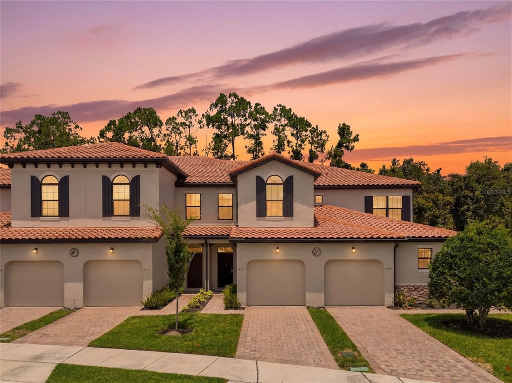 A two-story townhouse with a tile roof, four garage doors, and a paved driveway — 8129 ROSEVILLE ROAD, DAVENPORT, FL