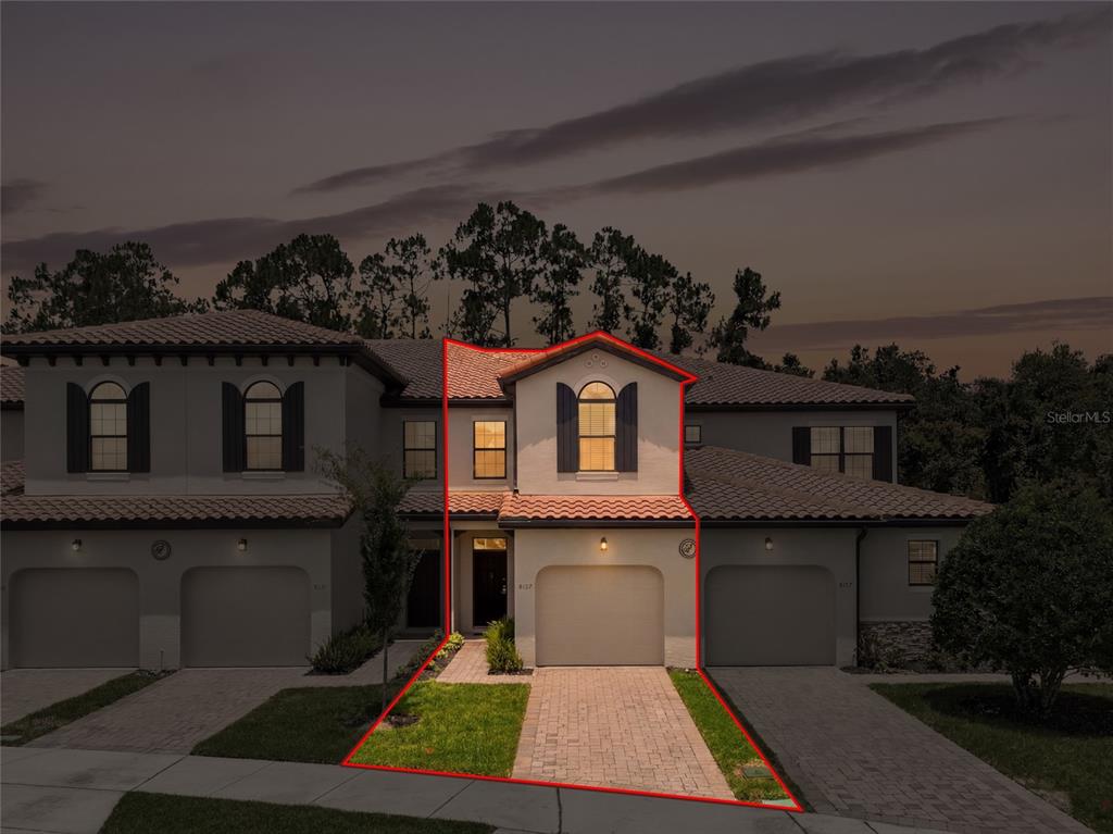 A two-story townhouse unit with a garage and a paved driveway at dusk — 8129 ROSEVILLE ROAD, DAVENPORT, FL