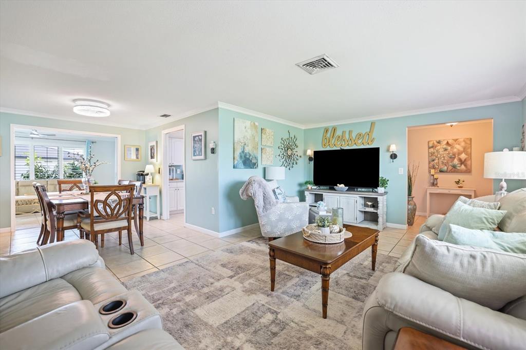 A living room with light blue walls, tile flooring, a television, and a dining area — 1330 CAMBRIDGE DRIVE, VENICE, FL