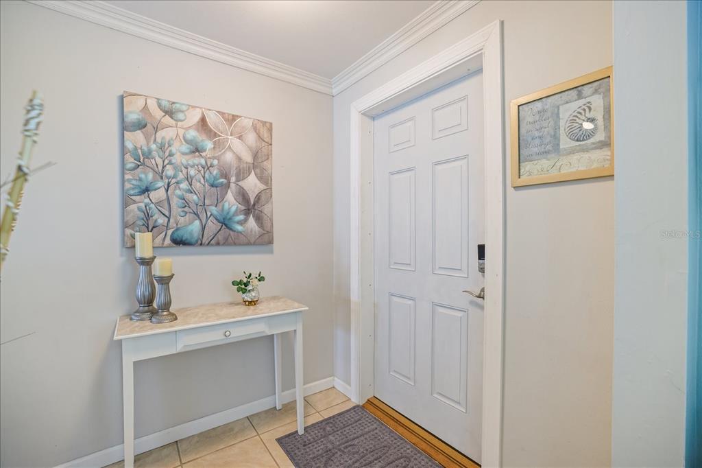 An entryway features a white console table, wall art, and a white six-panel front door — 1330 CAMBRIDGE DRIVE, VENICE, FL