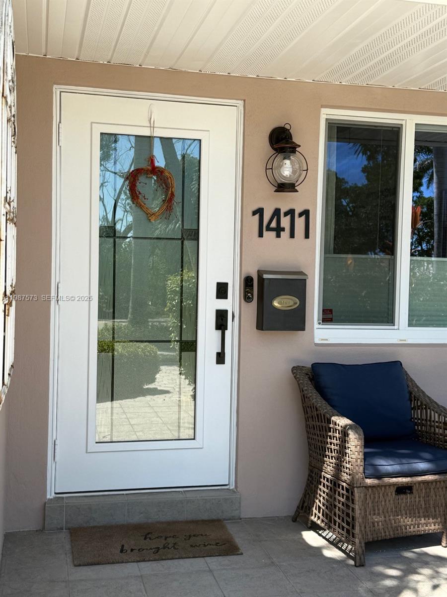 A white front door with a glass panel and a wicker chair on a porch — 1411 Harding St, Hollywood FL 33020, HOLLYWOOD, FL