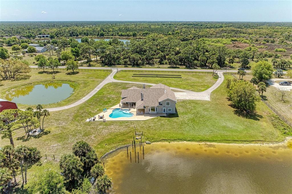 An aerial view shows a house with a pool situated between two ponds — 770 BUCKSKIN COURT, ENGLEWOOD, FL