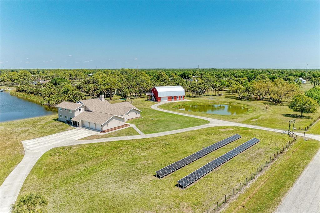 An aerial view shows a house, a red barn, a pond, and ground-mounted solar panels — 770 BUCKSKIN COURT, ENGLEWOOD, FL