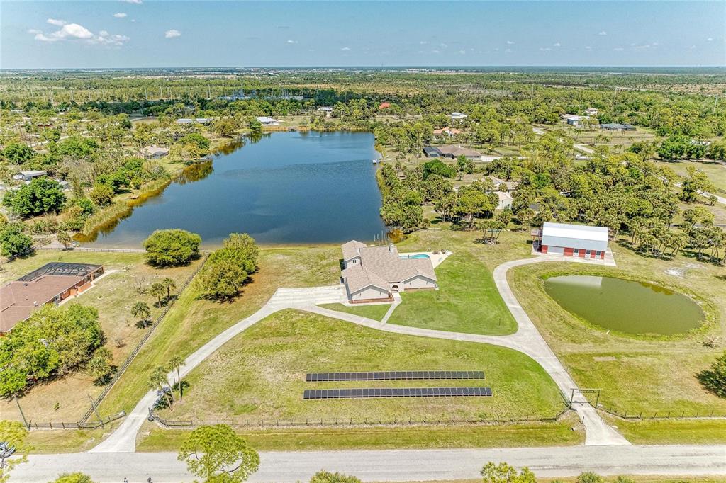 An aerial view shows a house with a pool, solar panels, and two ponds — 770 BUCKSKIN COURT, ENGLEWOOD, FL