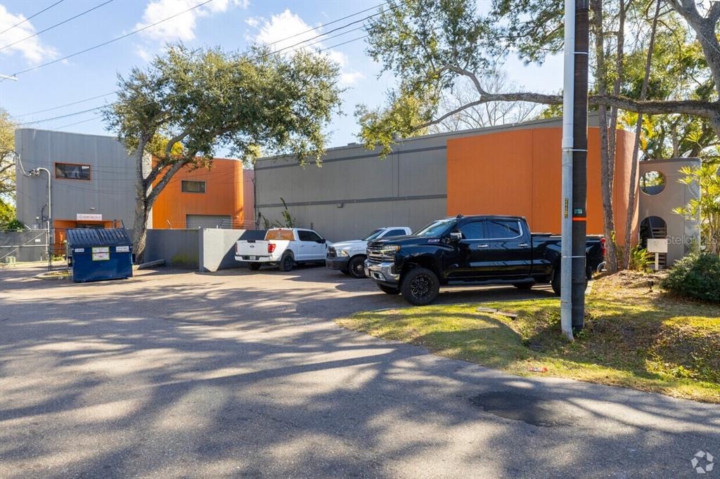 A parking lot with a blue dumpster and three pickup trucks in front of industrial buildings — 1207 N HIMES AVENUE UNIT 2, TAMPA, FL