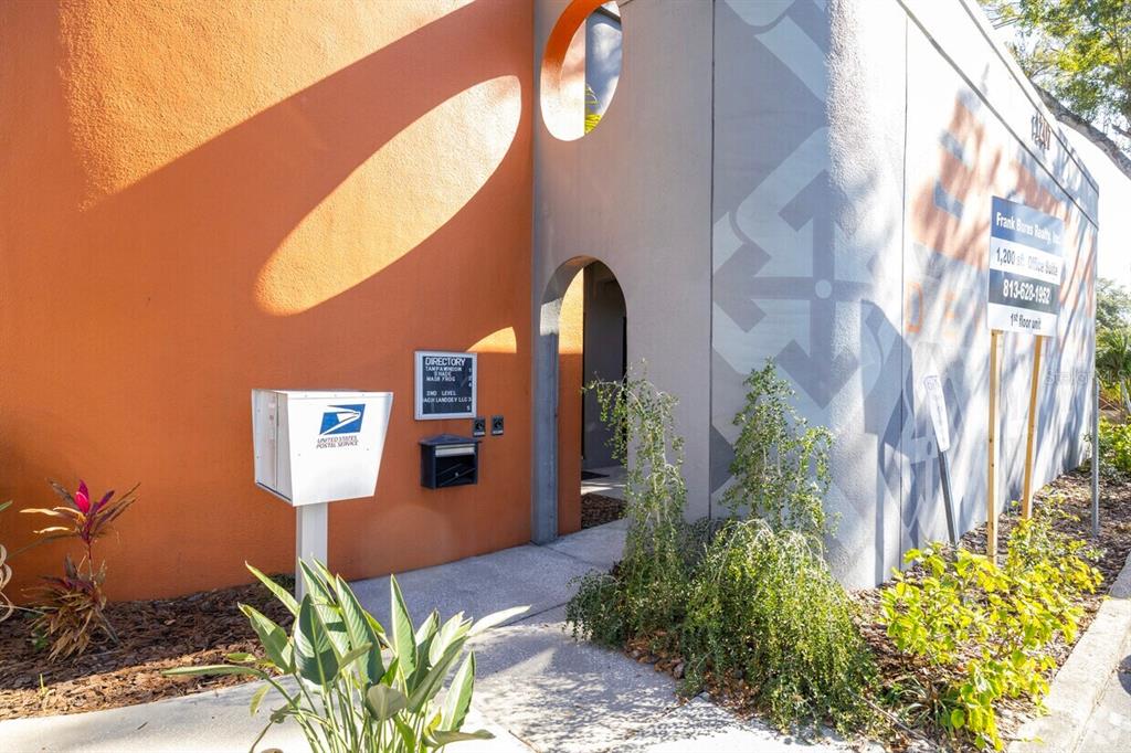 An exterior view of a building entrance with an orange wall, a mailbox, and signage — 1207 N HIMES AVENUE UNIT 2, TAMPA, FL