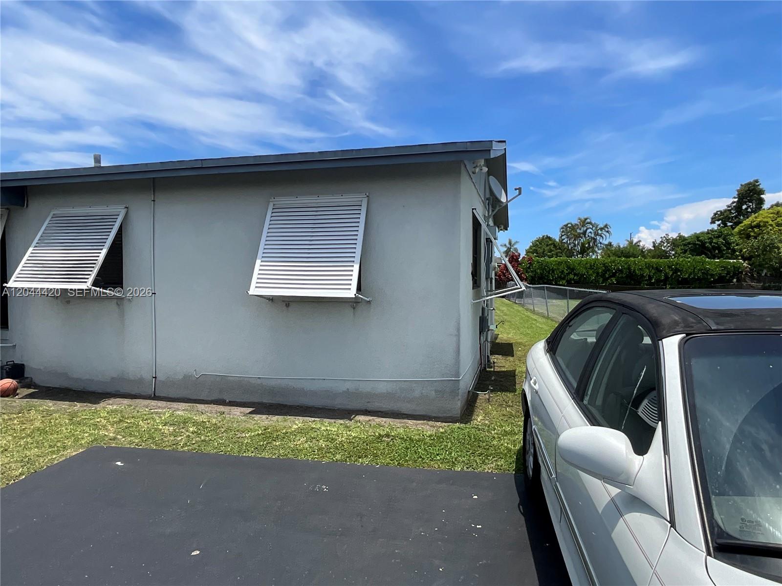 The exterior of a house features two white louvered window awnings and a parked car — 14253 SW 107th Pl # X, Miami FL 33176, MIAMI, FL