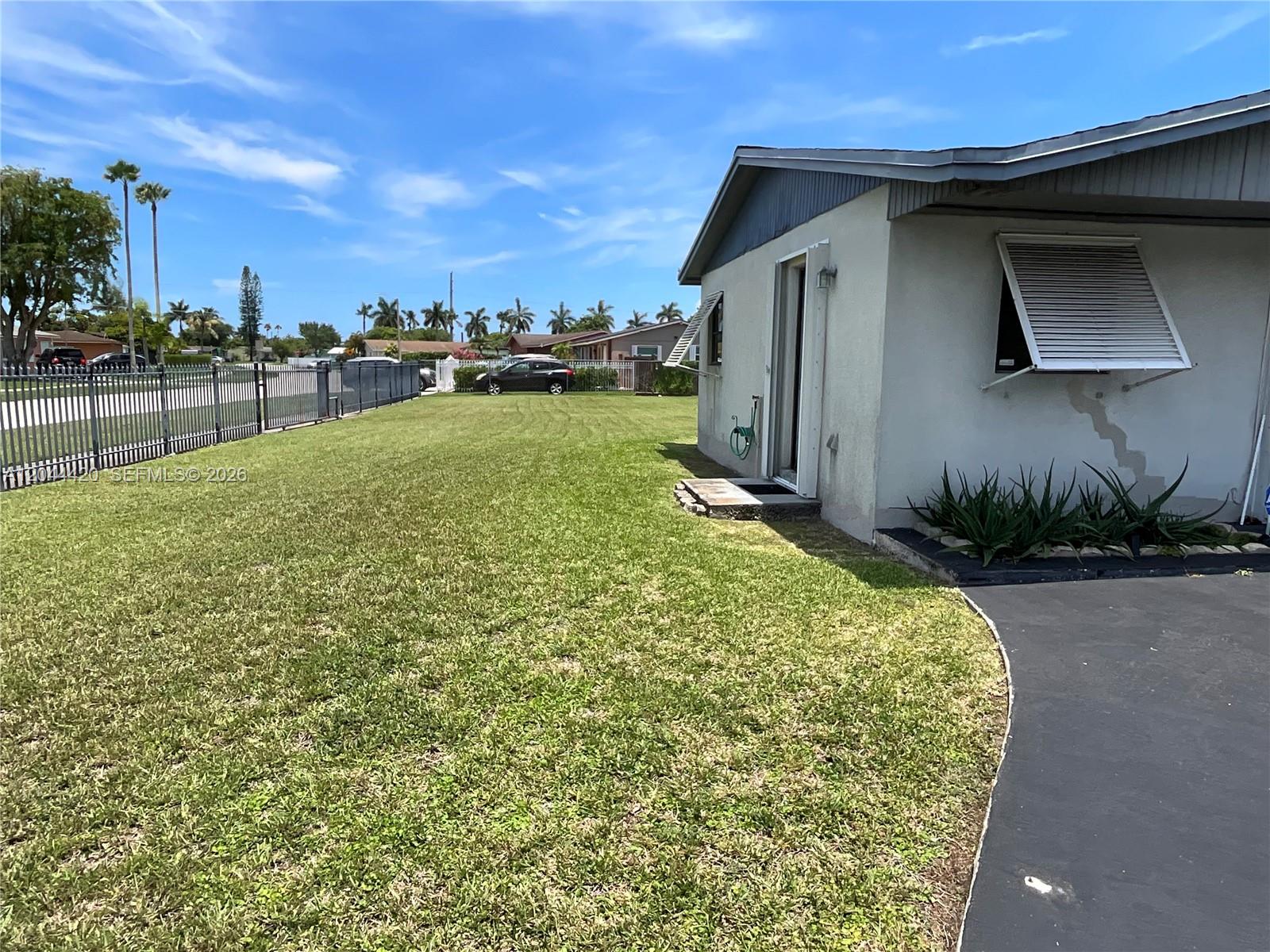 A side view of a house exterior shows a lawn, driveway, and metal window awning — 14253 SW 107th Pl # X, Miami FL 33176, MIAMI, FL